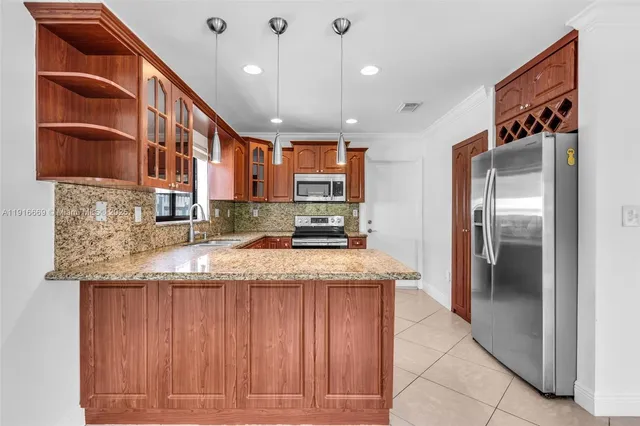 a kitchen with stainless steel appliances granite countertop a sink and a refrigerator