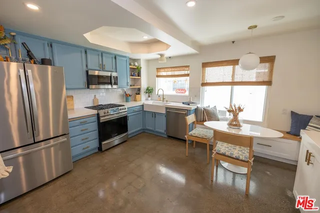 a kitchen with stainless steel appliances granite countertop a refrigerator a stove a sink dishwasher a dining table and chairs with wooden floor