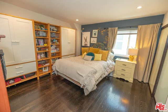 a bedroom with a bed and a large window with wooden floor