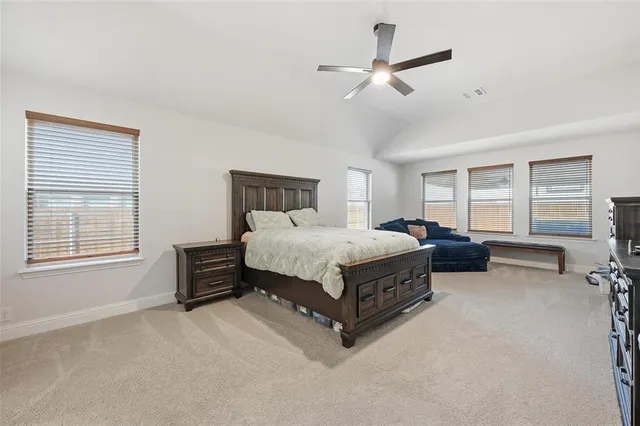 a spacious bedroom with a bed a couch and a ceiling fan