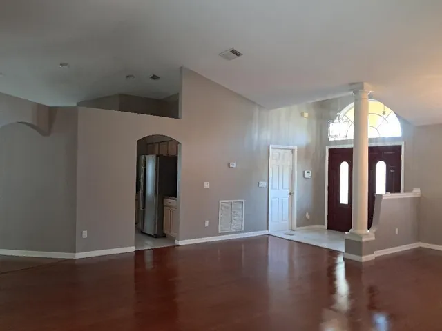 an empty room with wooden floor and windows