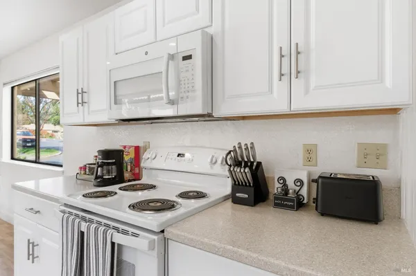 a kitchen with white cabinets and white appliances