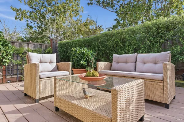 a view of a patio with couches and a table and chairs with wooden floor and fence