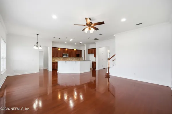 an empty room with wooden floor exposed radiator and windows