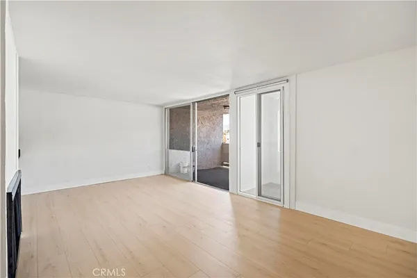 an empty room with wooden floor fireplace and windows