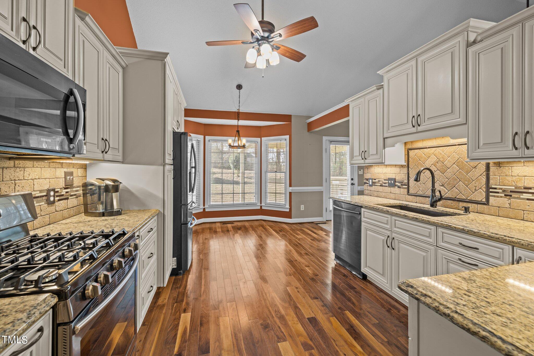 209 Priceview Drive Raleigh, NC 27603 - Photo 6 of 20 a kitchen with stainless steel appliances hardwood floor sink stove and wooden cabinets
