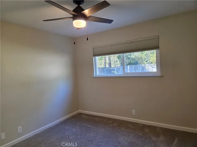 an empty room with a window and a fan