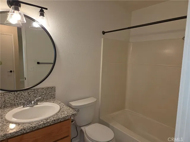 a bathroom with a granite countertop sink toilet and a mirror