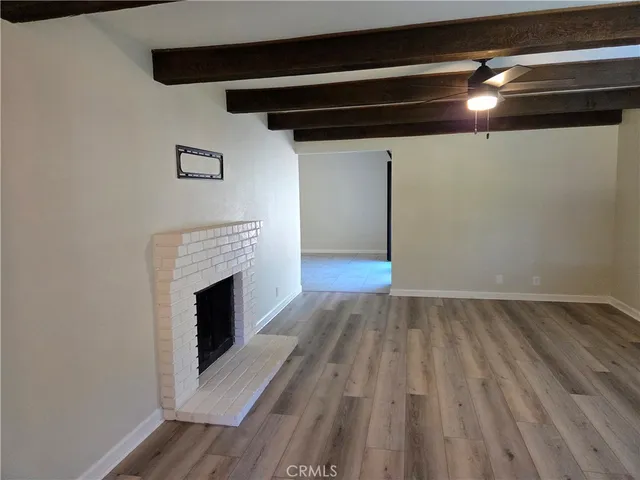 a view of empty room with wooden floor and fireplace