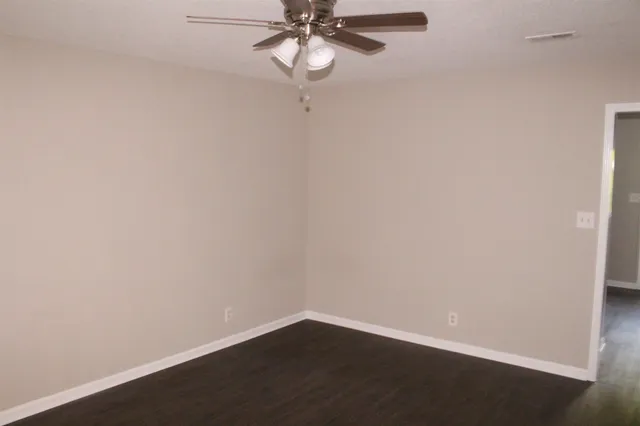 a view of a small space with wooden floor and fan