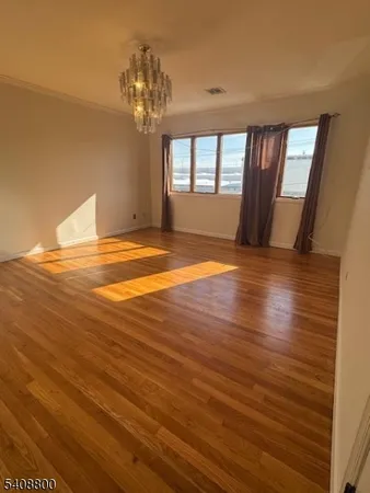 a view of empty room with window and wooden floor
