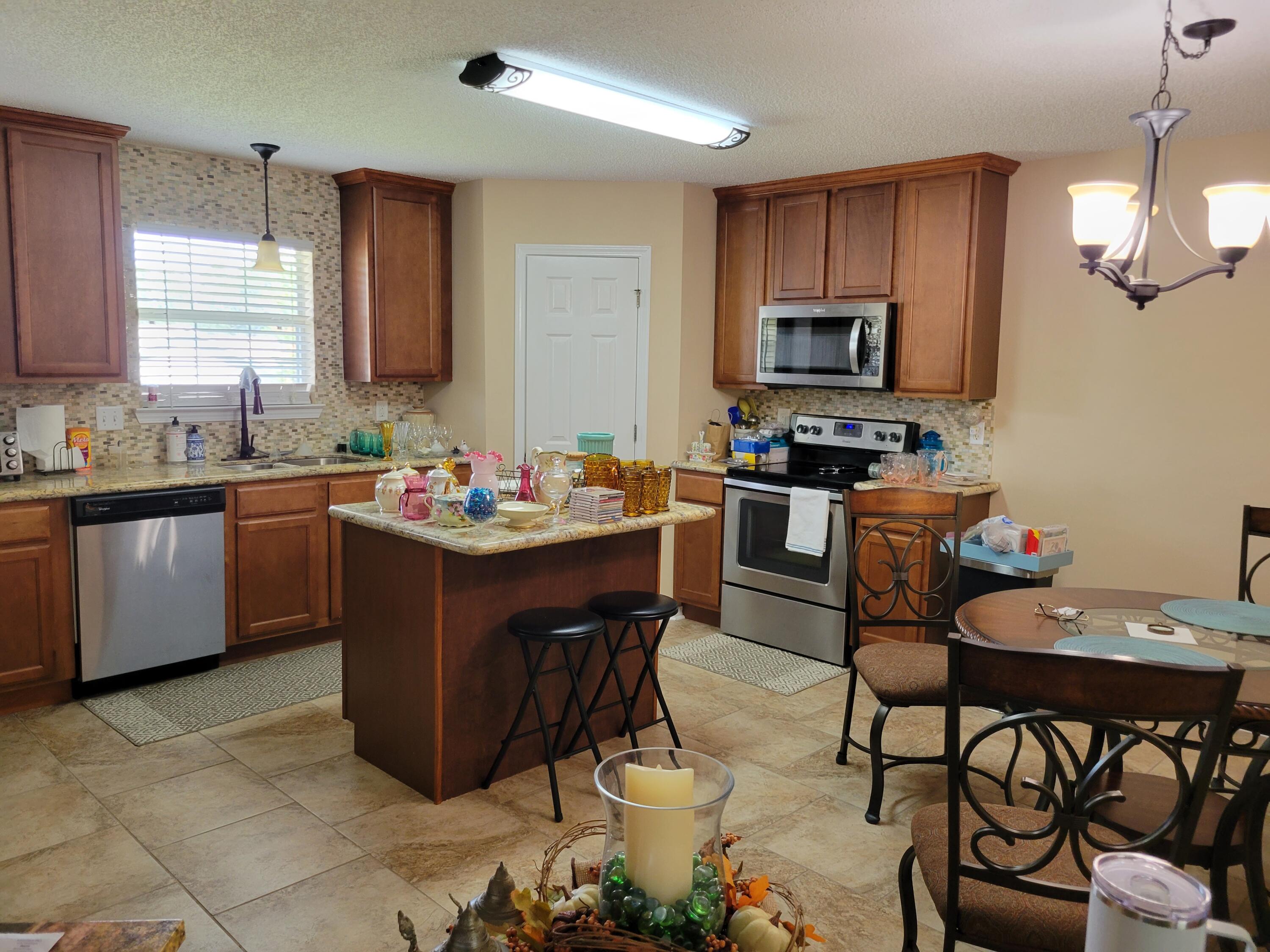 4712 Whitewater Lane Crestview, FL 32539 - Photo 22 of 25 a kitchen with a sink stove and chairs