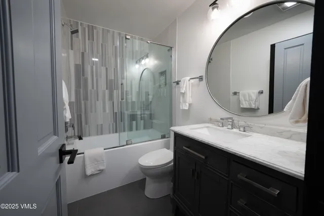 a bathroom with a double vanity sink toilet mirror and shower