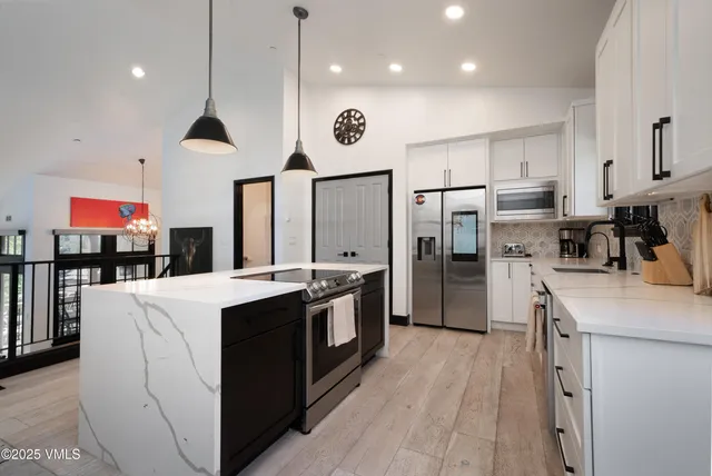 a large kitchen with stainless steel appliances kitchen island a large counter top a stove and a refrigerator