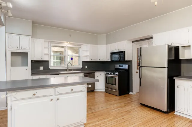 a kitchen with kitchen island a counter top space a refrigerator a stove a microwave and cabinets