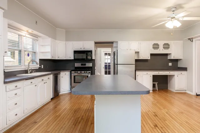 a kitchen with stainless steel appliances granite countertop a sink a stove top oven a counter space and cabinets