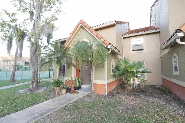 a view of a house with a yard and palm trees