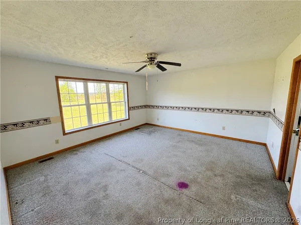 an empty room with windows and fan view