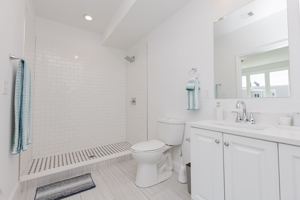 92-94 George Street, Unit 202 Boston, MA 02119 - Photo 28 of 42 a bathroom with a granite countertop sink a toilet and a mirror