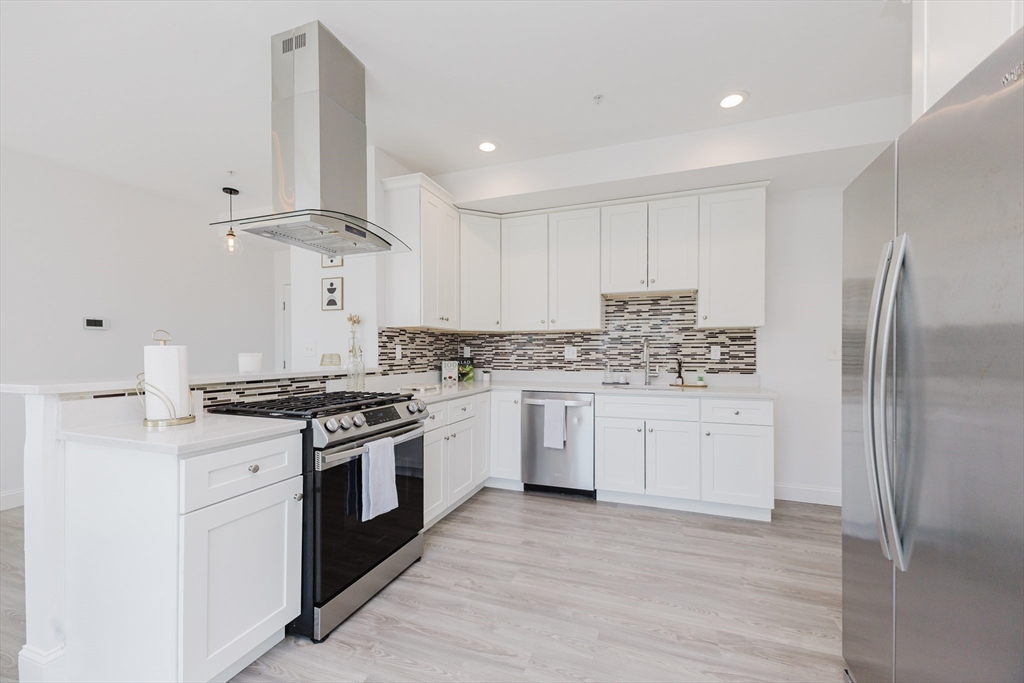 92-94 George Street, Unit 202 Boston, MA 02119 - Photo 6 of 42 a kitchen with granite countertop white cabinets and stainless steel appliances