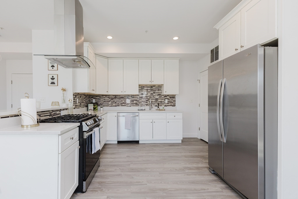 92-94 George Street, Unit 202 Boston, MA 02119 - Photo 10 of 42 a kitchen with stainless steel appliances granite countertop a stove a refrigerator and a refrigerator