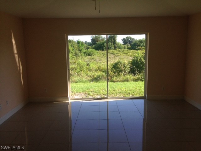 914 Alabama Road South Lehigh Acres, FL 33974 - Photo 3 of 6 a view of an empty room with wooden floor and a window