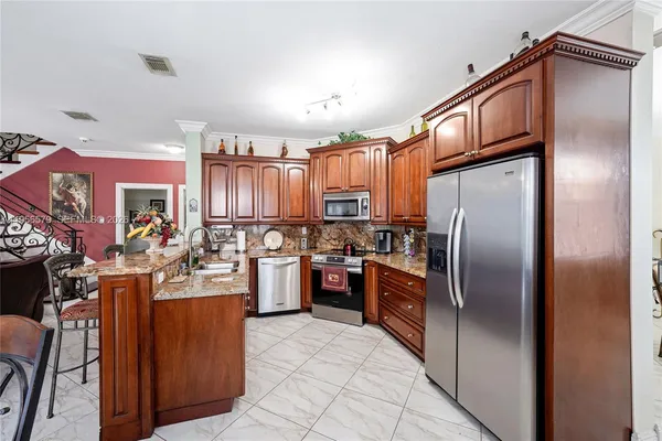 a kitchen with stainless steel appliances granite countertop a refrigerator a sink dishwasher a oven with a dining table and chairs