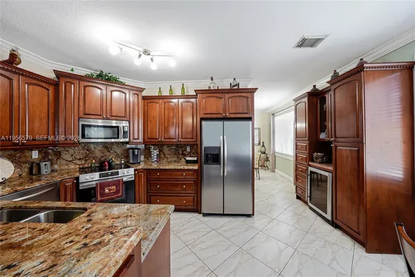 a kitchen with granite countertop a refrigerator and a stove top oven