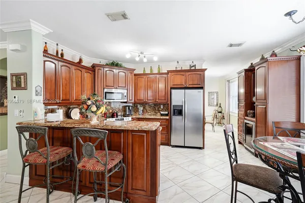 a kitchen with granite countertop a table chairs refrigerator and microwave