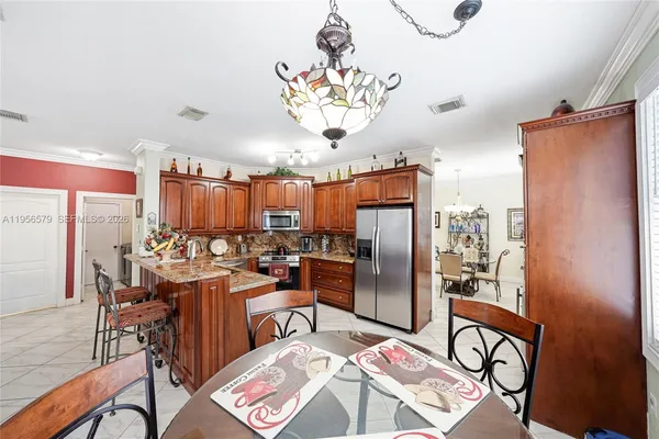 a kitchen with stainless steel appliances a dining table chairs stove refrigerator and cabinets