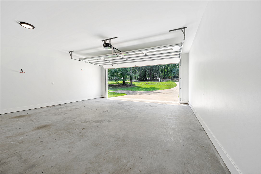 516 Winding Way Hartwell, GA 30643 - Photo 27 of 50 A spacious, clean garage with an open door leads to a verdant outdoor landscape.