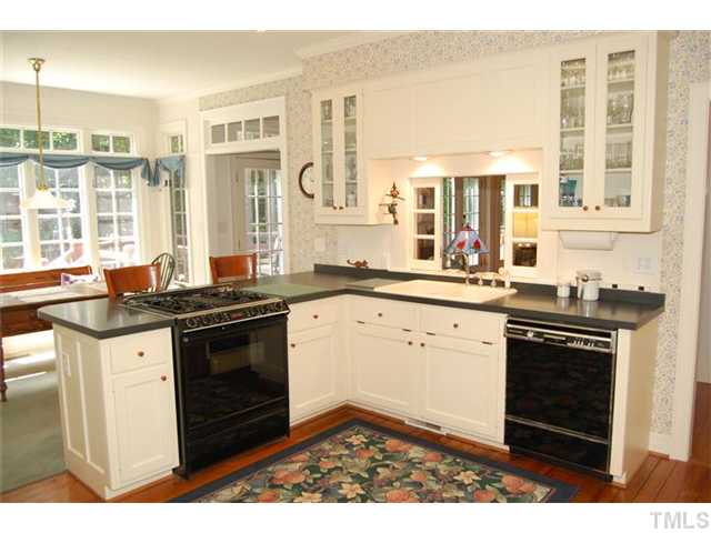 Charming kitchen accented by off-white cabinets and pocket doors above the sink. 165 yr old heart pine floors! Spacious and sunny breakfast room, too.