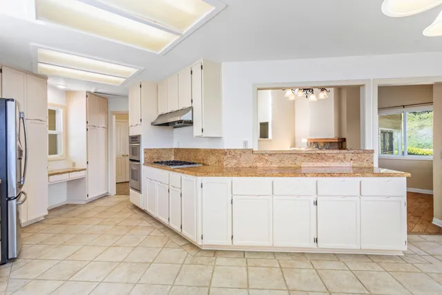 a large white kitchen with granite countertop a sink