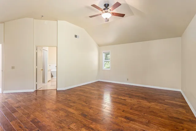 an empty room with wooden floor fan and windows