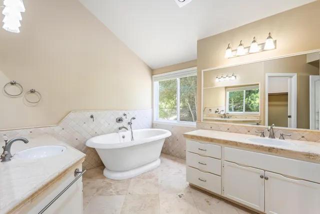 a spacious bathroom with a double vanity sink large mirror and bathtub
