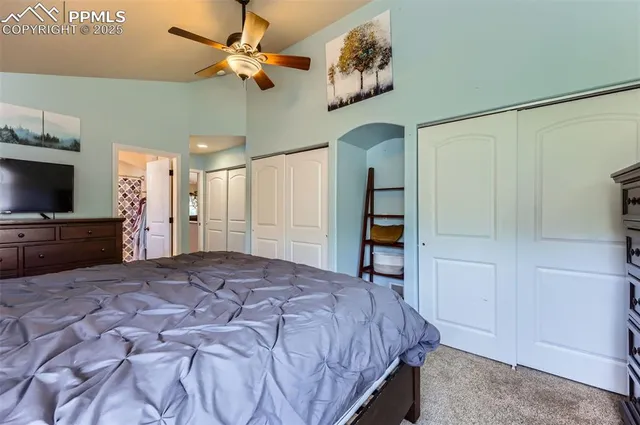 a spacious bedroom with a bed and a flat tv screen on dresser