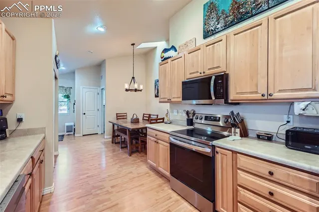 a kitchen with stainless steel appliances a stove top oven a sink a dining table and chairs