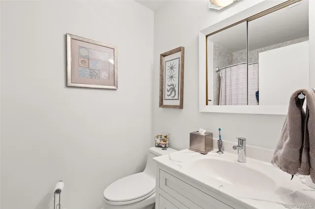 a bathroom with a granite countertop toilet sink and mirror