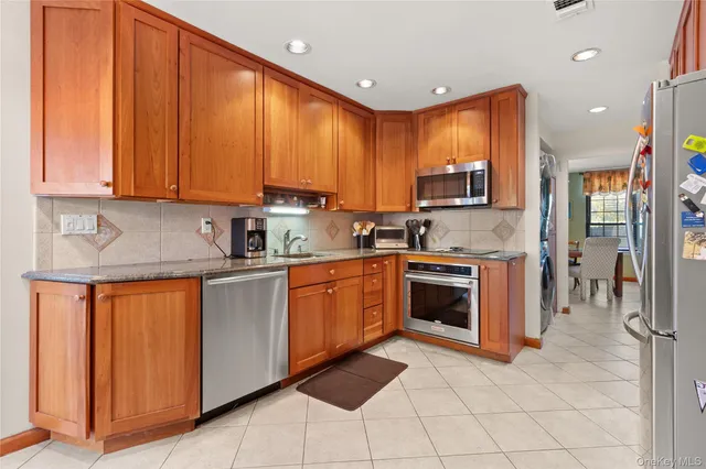 a kitchen with stainless steel appliances granite countertop a stove a sink dishwasher and a refrigerator