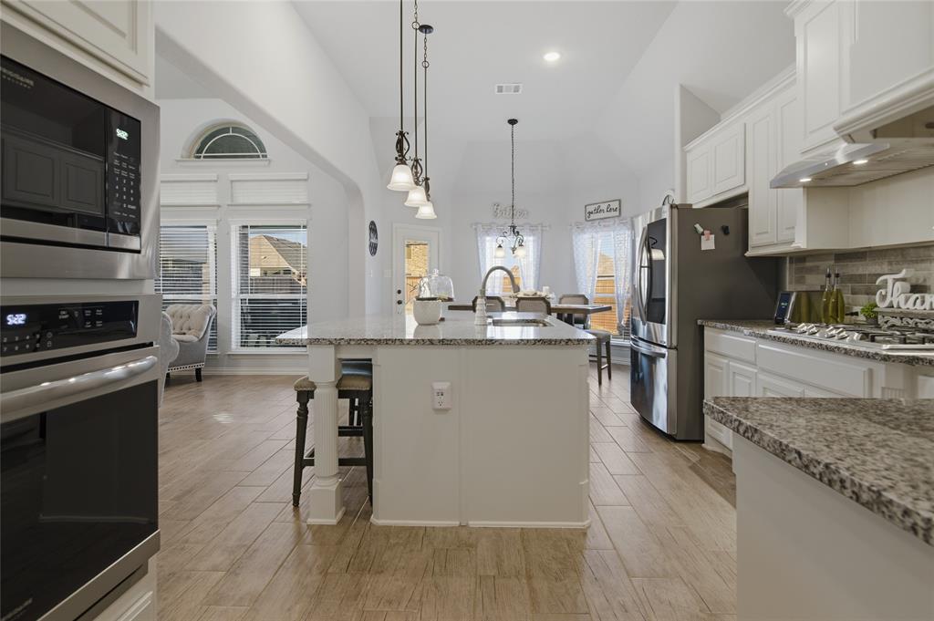 464 LeTara Ranch Drive Haslet, TX 76052 - Photo 13 of 37 Expansive kitchen featuring a large island with pendant lighting, stainless steel appliances, white cabinetry, granite countertops, and wood-finish flooring