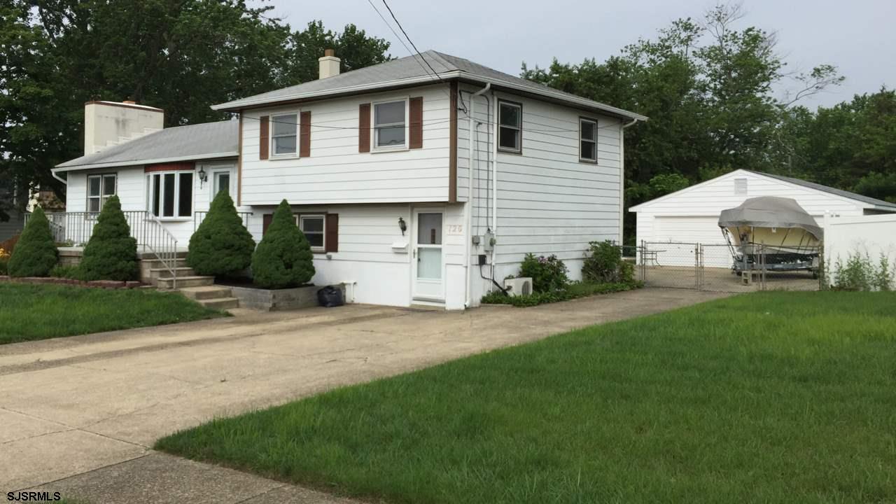 a view of a white house next to a yard and trees