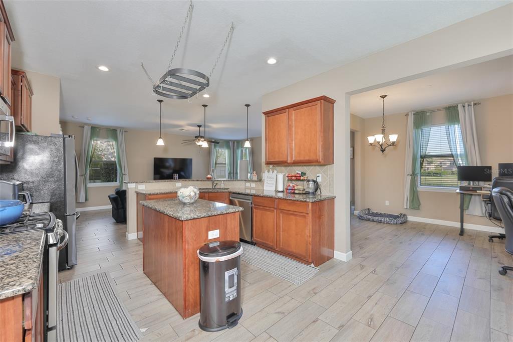 5779 Aaron Court Sarasota, FL 34232 - Photo 12 of 39 a kitchen with stainless steel appliances kitchen island granite countertop a stove a refrigerator a sink a dining table and chairs with wooden floor