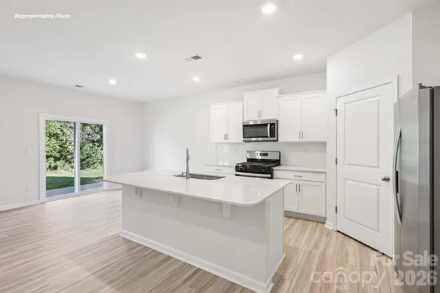 a kitchen with stainless steel appliances a stove top oven a sink a refrigerator a window