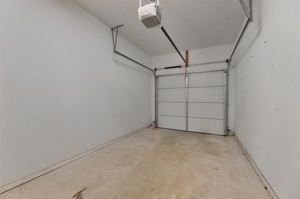 1713 Bronco Road Granbury, TX 76049 - Photo 11 of 23 Single-car garage featuring a paneled overhead door, automatic opener, concrete flooring, and painted walls