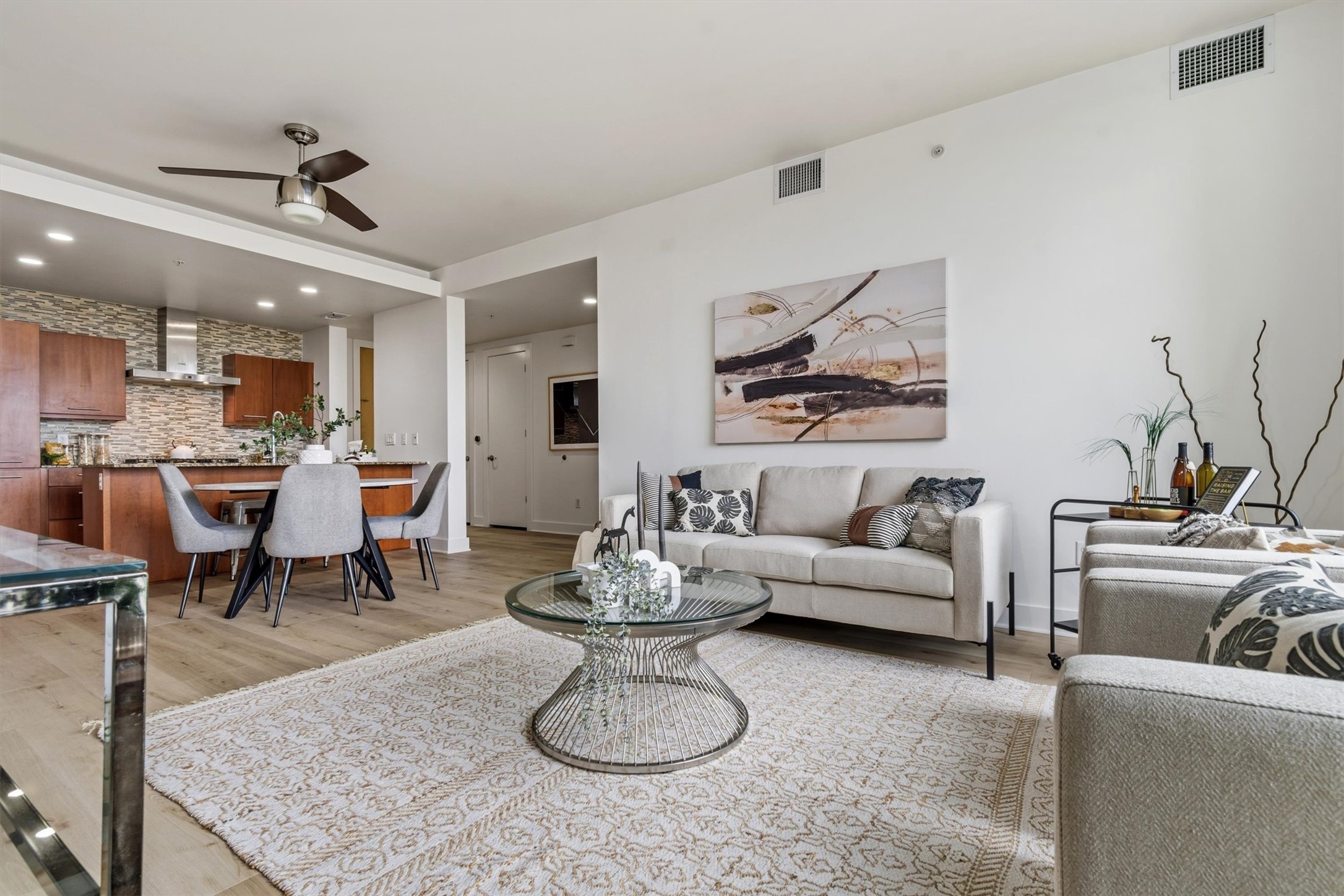 Open-concept layout connecting living and kitchen areas with luxury vinyl plank flooring and contemporary designer finishes.