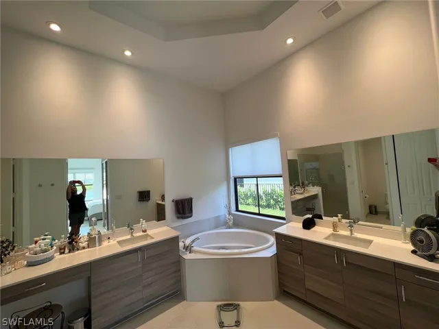a bathroom with a double vanity sink toilet mirror and bathtub