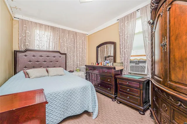 a bedroom with a bed and a dresser next to a window