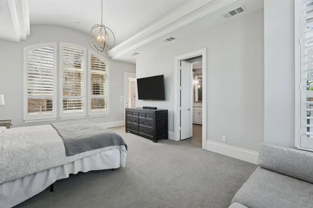 a spacious bedroom with a bed and a flat screen tv