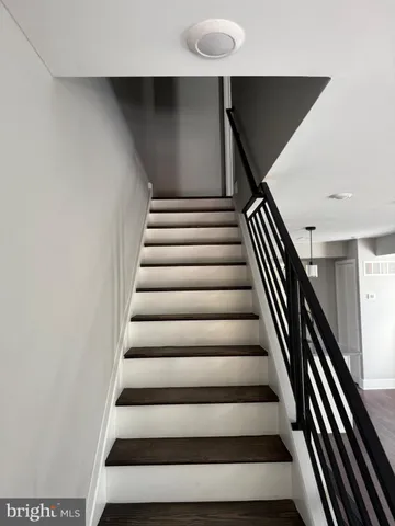 a kitchen with stainless steel appliances granite countertop a sink a stove top oven a refrigerator with white cabinets and wooden floor