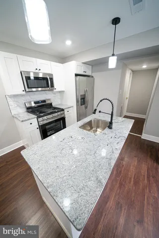 a kitchen with stainless steel appliances granite countertop a stove a sink dishwasher and a refrigerator with wooden floor